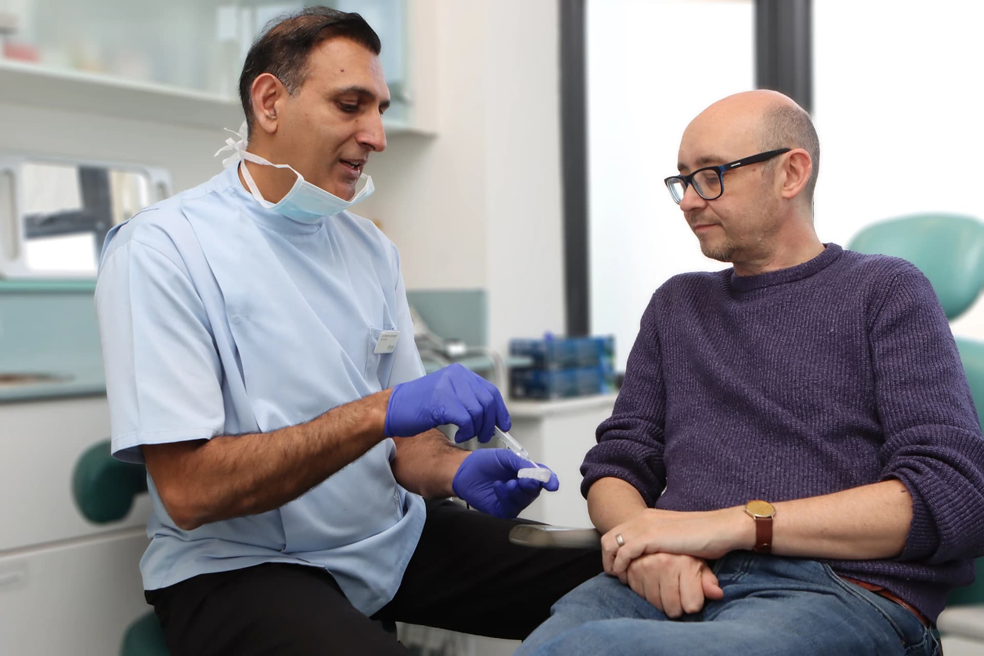 Dentist assessing tooth shade and sensitivity during whitening consultation.